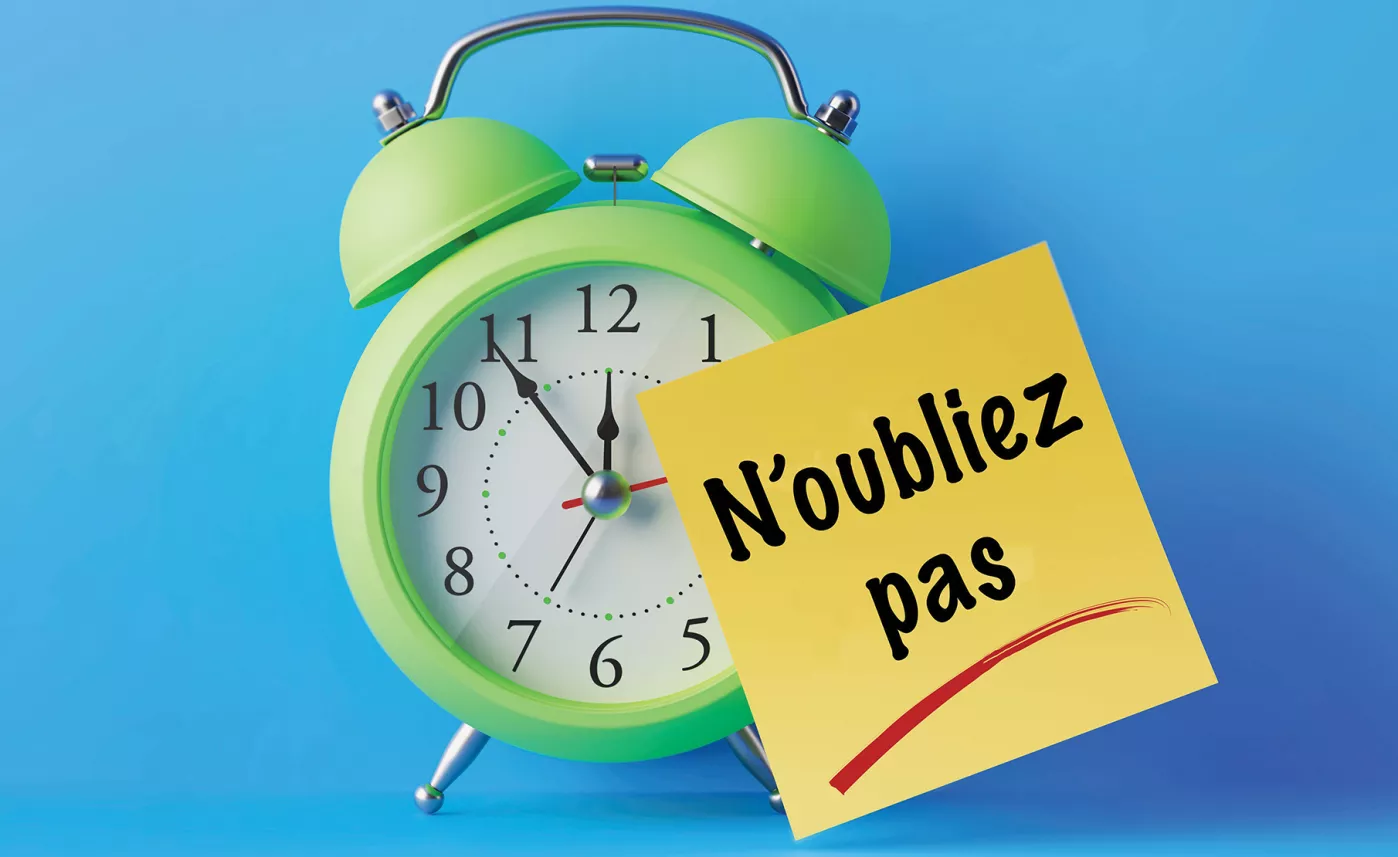  Une horloge verte avec un post-it attaché indiquant « N'oubliez pas »
