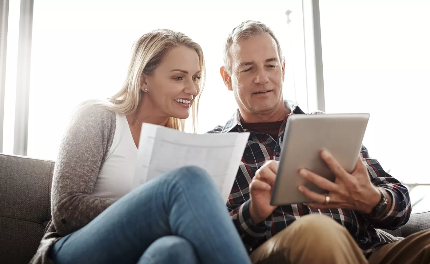  Un couple assis sur le divan passe en revue les renseignements relatifs à l’homologation sur une tablette.
