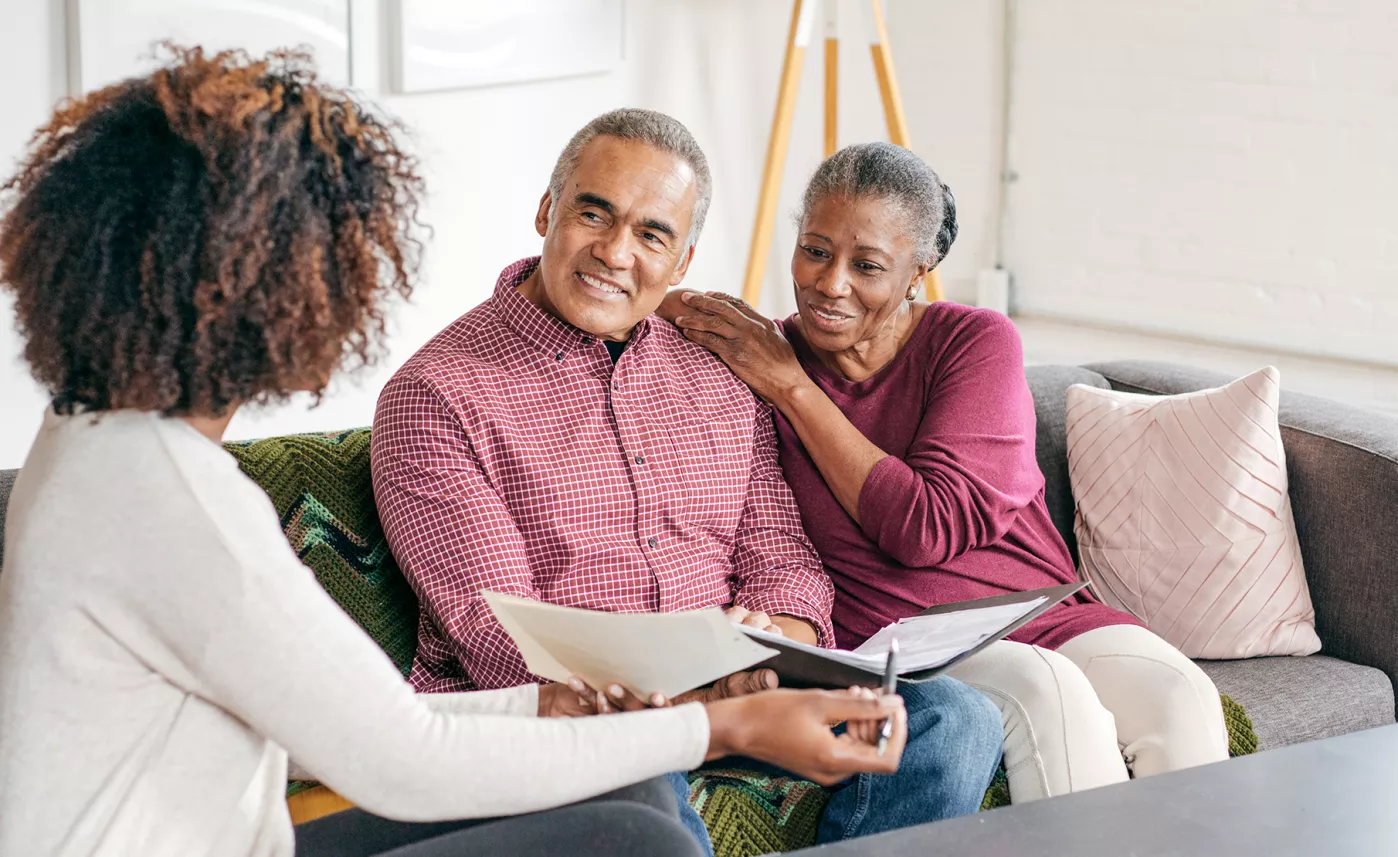  An elderly couple listens to their younger daughter discuss information in an official-looking document.
