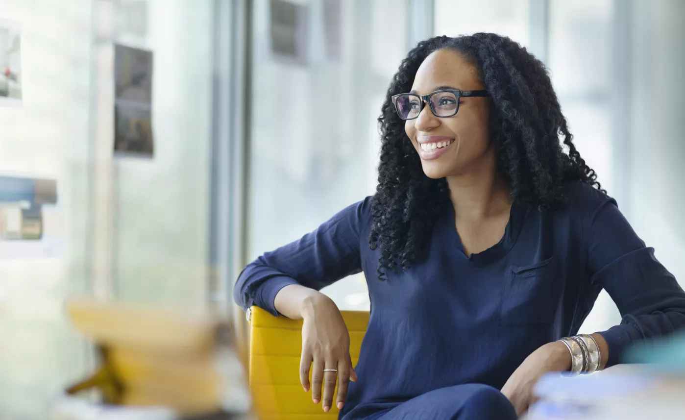  A young person smiles in a brightly-lit office.
