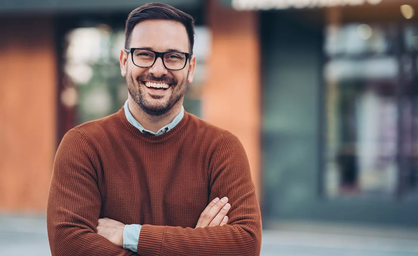  A young man smiles outside of a storefront.
