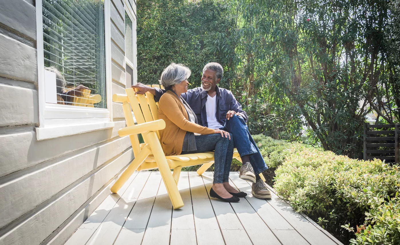  Un couple âgé sourit sur le balcon par une journée ensoleillée.
