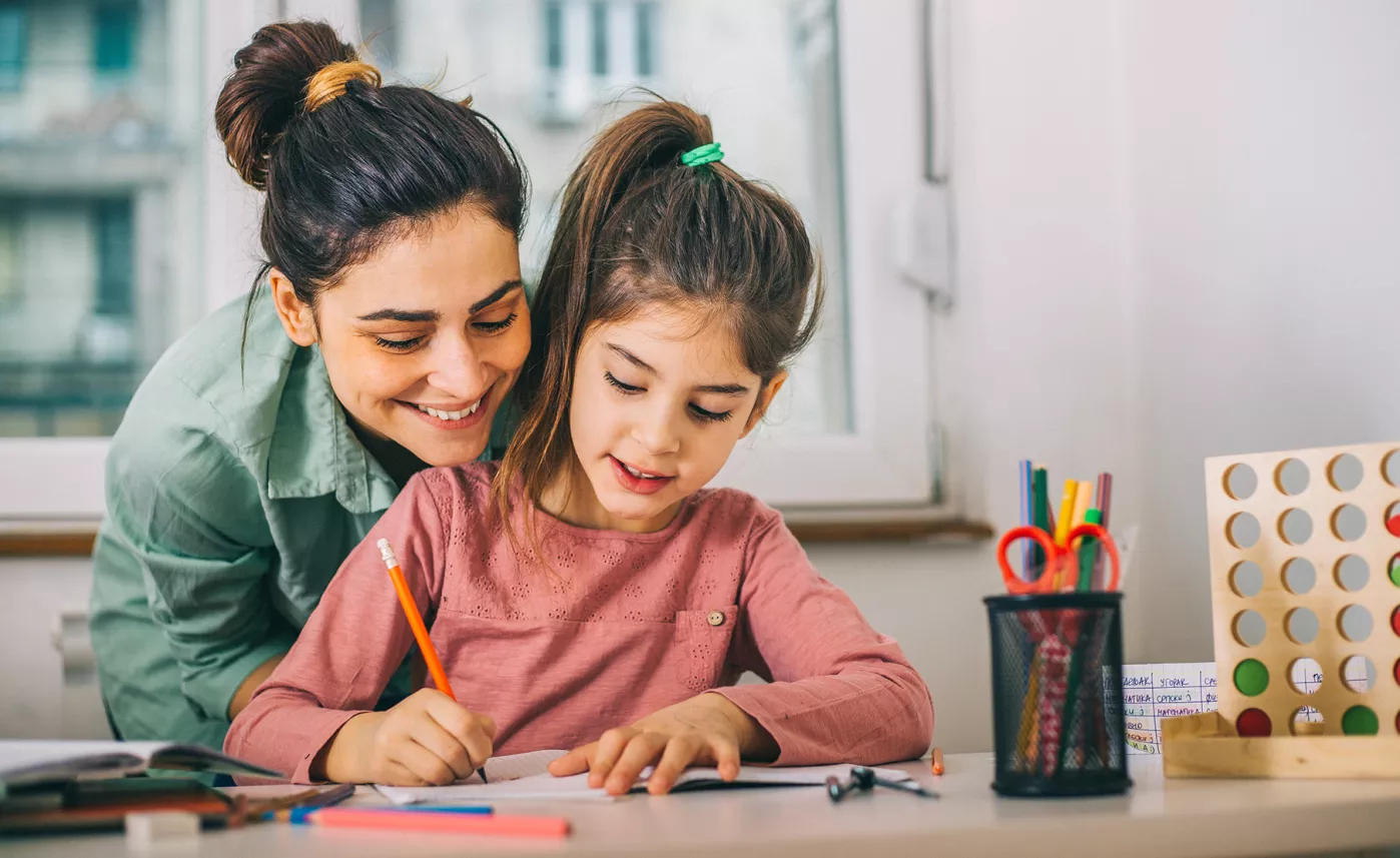  A mother helps her young daughter with her homework.
