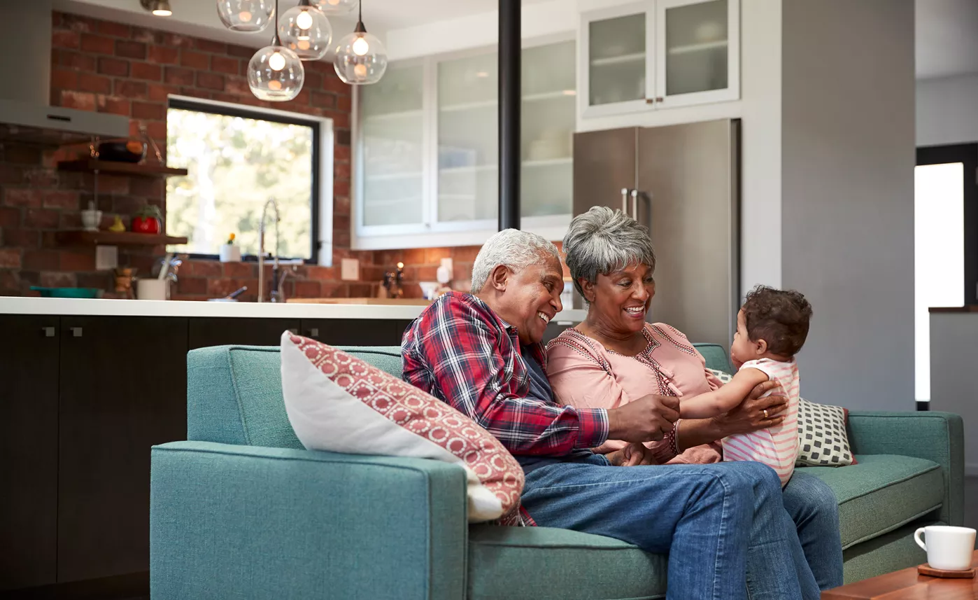  Two grandparents sit with their infant son in their home.
