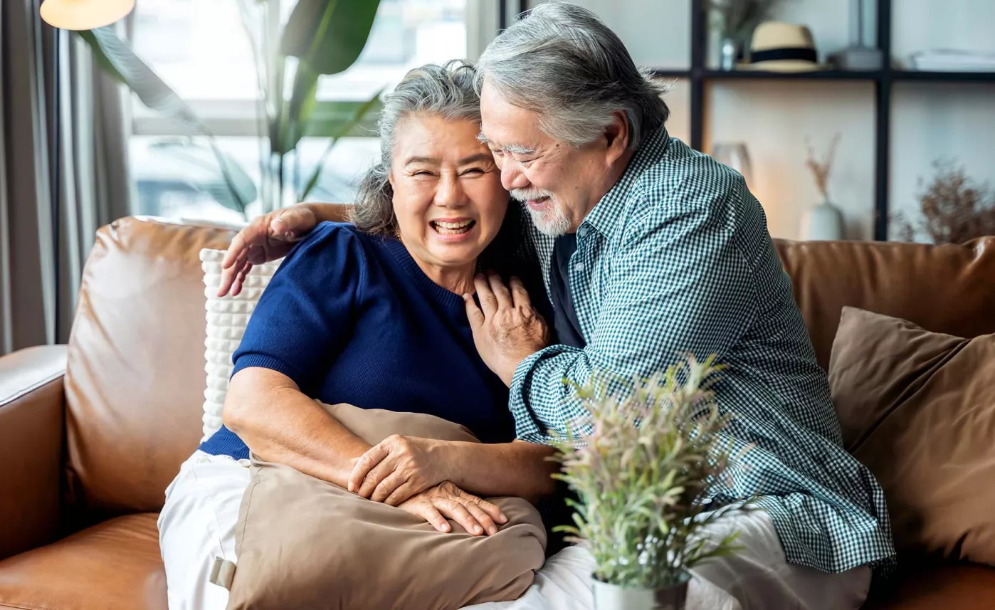  A mature couple sitting on a couch, laughing together
