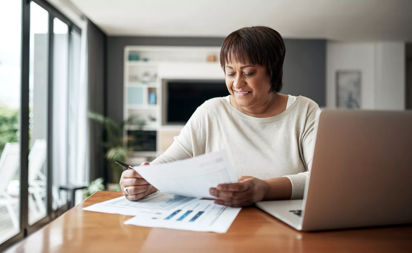  A woman smiles as she reads financial information on her tablet in her living room.
