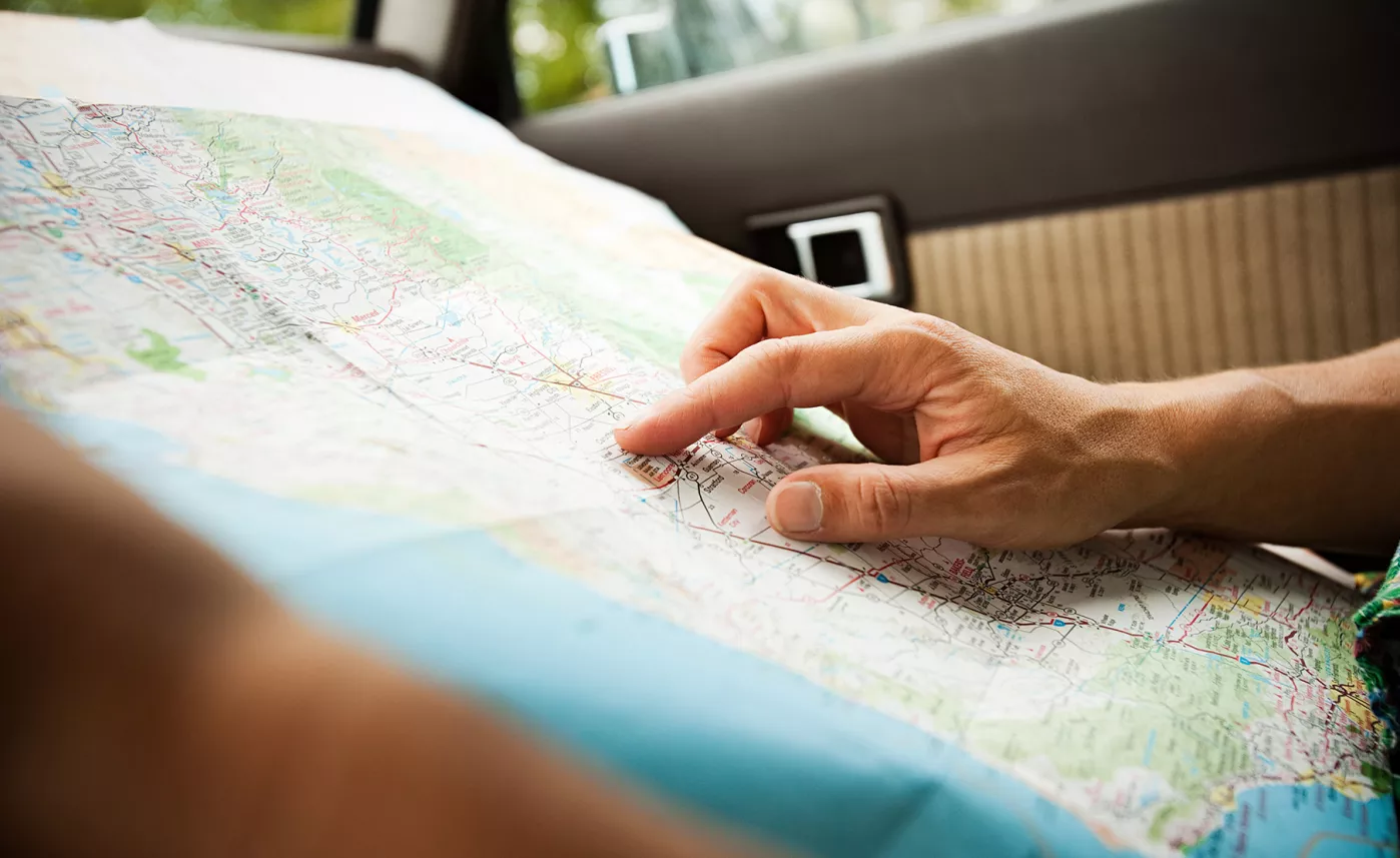  Close-up of hands tracing a route on a paper map.
