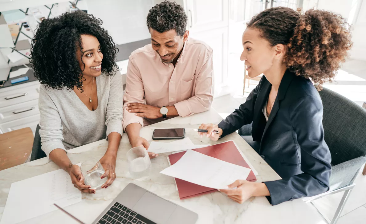  An Edward Jones advisor discusses financial documents with two clients in her office.
