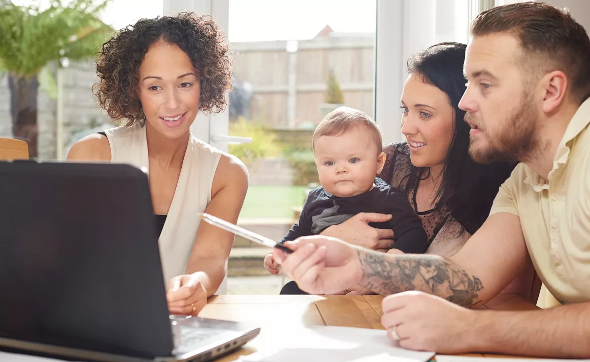  An Edward Jones advisor assists young parents, with their infant son, with learning about their savings options.
