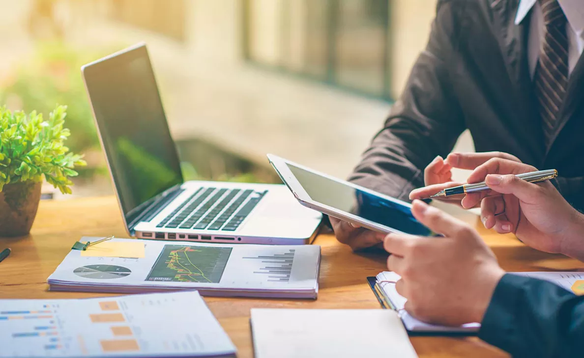  An Edward Jones advisor works with a client to educate him on stocks, surrounded by data and reports for their discussion.
