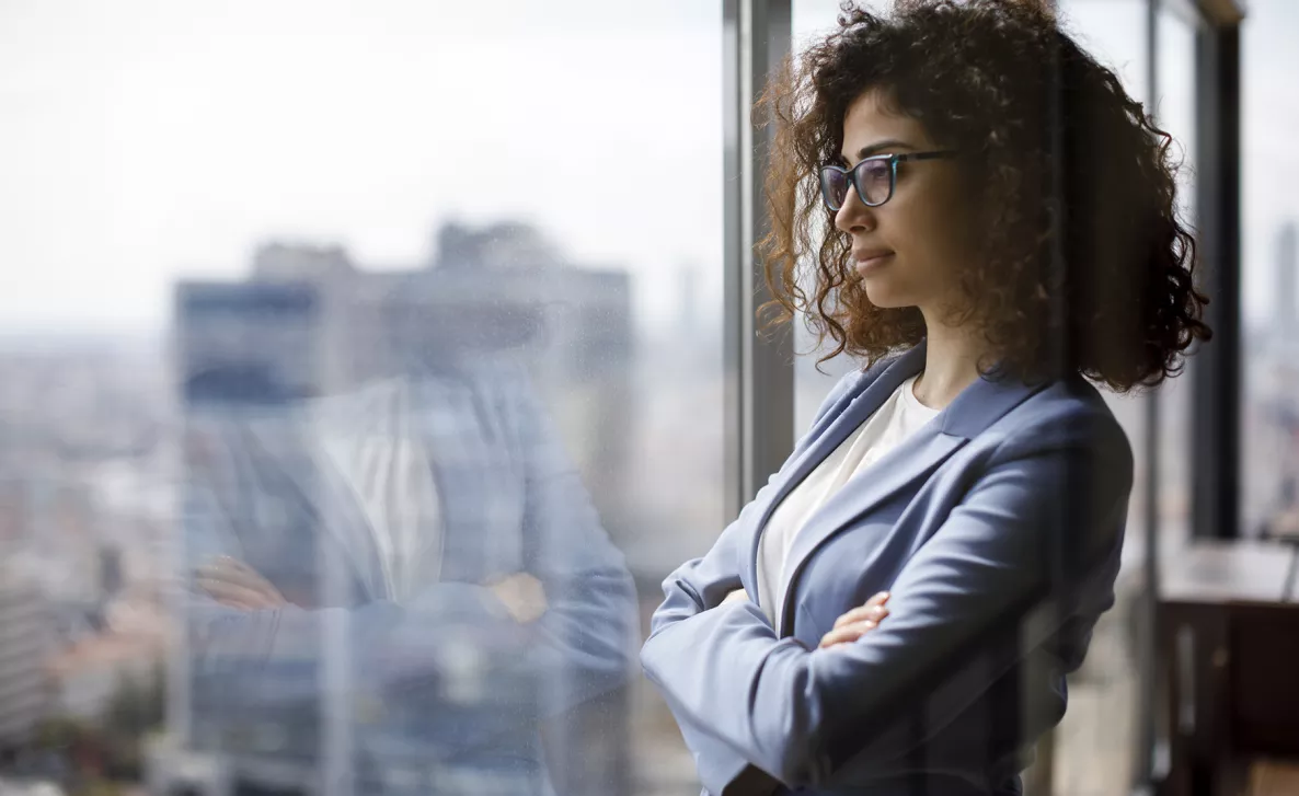  A woman confidently looks out a window on the first day of her new job.
