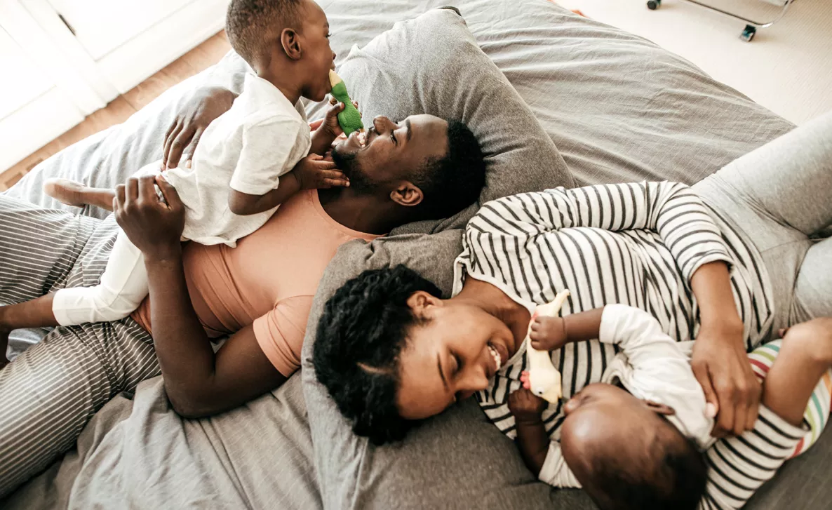  A couple, each holding a young child, laughing together.
