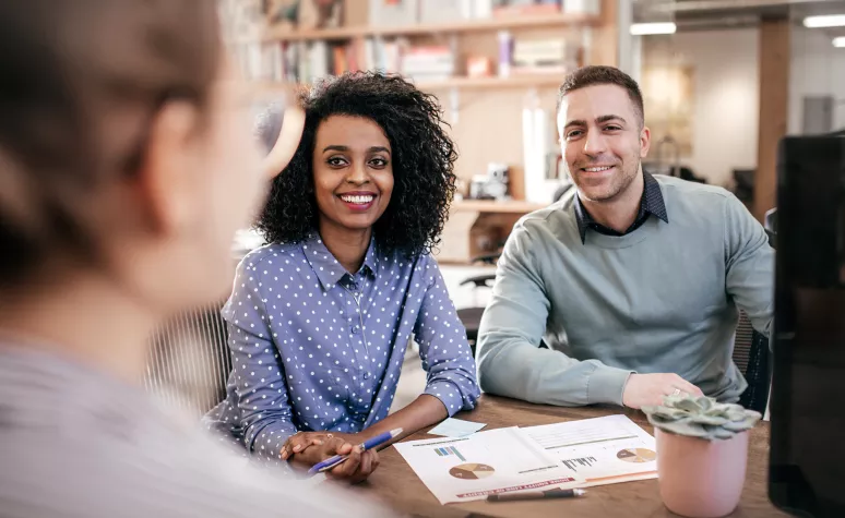 A young couple listens to their Edward Jones financial advisor during a meeting at a cafe.