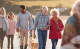 Une grande famille marche ensemble sur la plage.