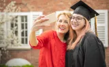 A mother takes a photo with her daughter at graduation.