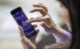 A woman searches stock market news on her smartphone.