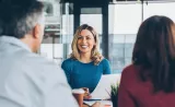 Un conseiller financier sourit et discute de planification avec un couple d’âge moyen.