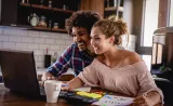 A young couple reviews their estate strategy together at home on a laptop.