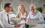 An Edward Jones financial advisor speaks with two senior clients in his branch office.