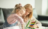 A young mother and her daughter work on a puzzle game together.