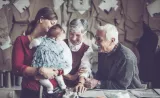 Two grandparents visit with their daughter and granddaughter.