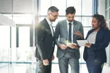 Three Edward Jones associates discuss finances in a modern office building.