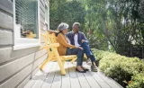 Un couple âgé sourit sur le balcon par une journée ensoleillée.