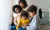 A family sits together while one child plays on a tablet.